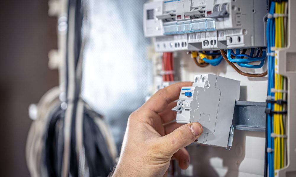 Male electrician at the checkout counter on a blurred background of a switchboard.