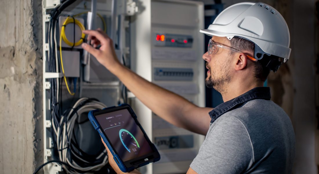 Man, an electrical technician working in a switchboard with fuses. Installation and connection of electrical equipment.