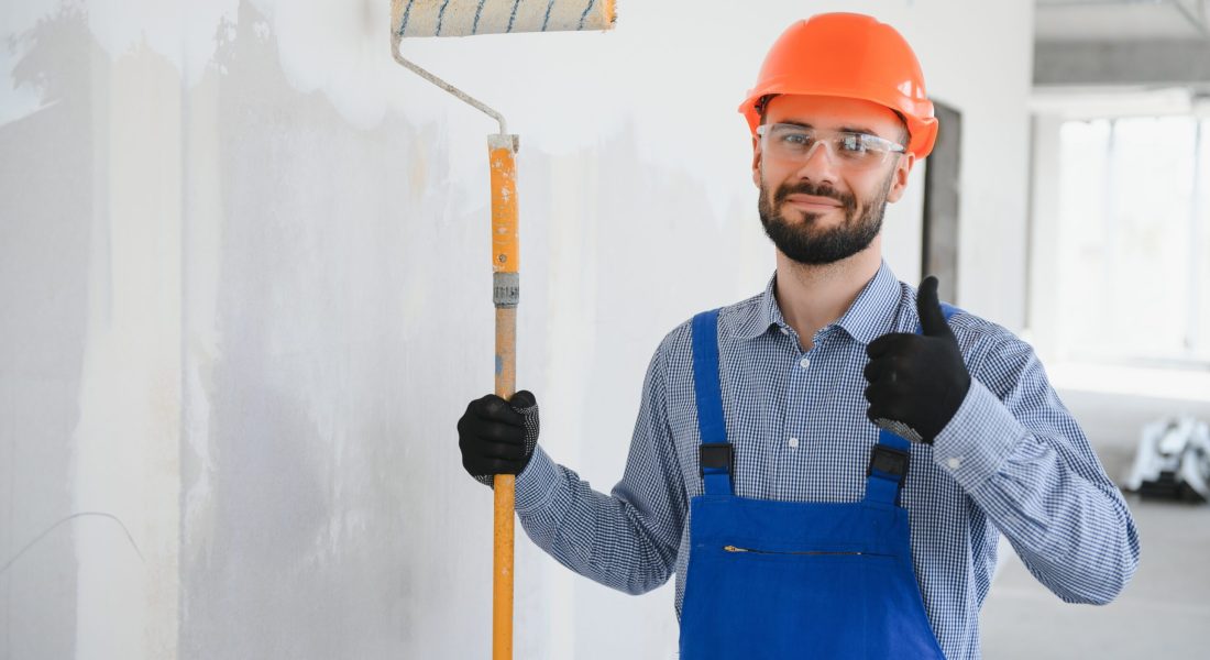 Portrait of young and hardworking constructor posing in big unfinished room. Building concept.